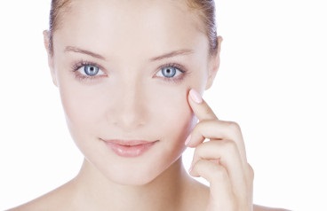 A young woman with blue eyes, finger touching her face